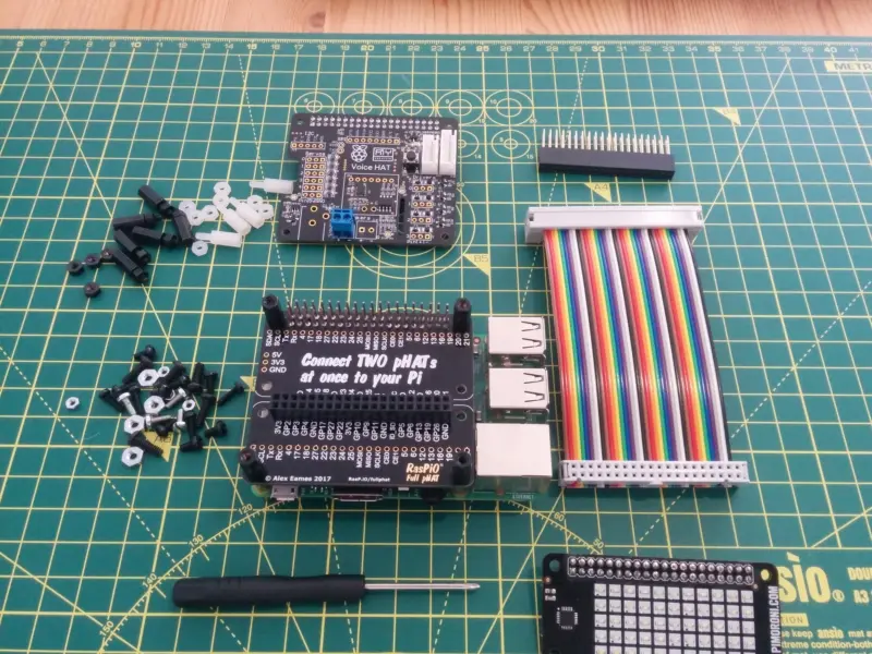 More RaspberryPi bits, partially assembled; a full pHAT board that allows for two headers to be attached to a RaspberryPi, GPIO cable, ScrollpHAT and the GoogleAIY Voice HAT.