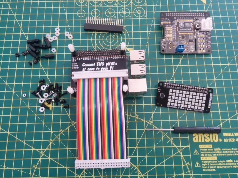 The full pHAT and multicoloured GPIO cable connected on top of the RaspberryPi. The ScrollPHAT is to one side awaiting connection to the GoogleAIY kit.