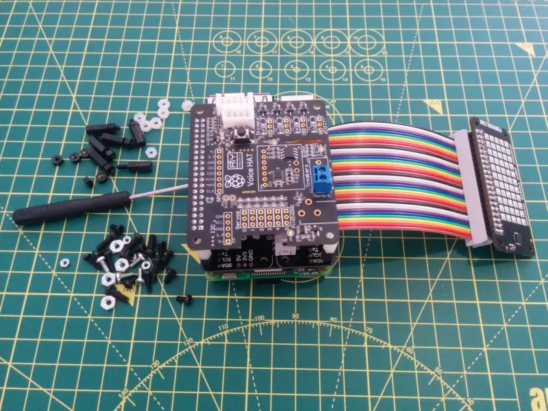 A side view of the full pHAT, multicoloured GPIO, the RaspberryPi and the ScrollPHAT on the end of the cable. The GoogleAIY Voice Hat sits on top of the stack. The headers that seperate the boards are visible from this angle.