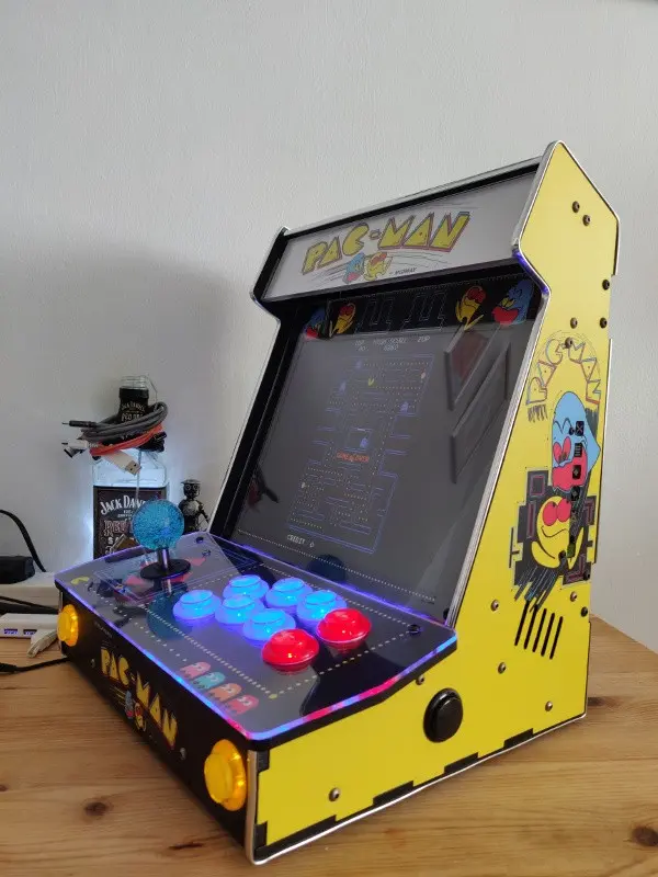 The completed cabinet shown from the side, all buttons illuminated and Pac-Man playing on the display.