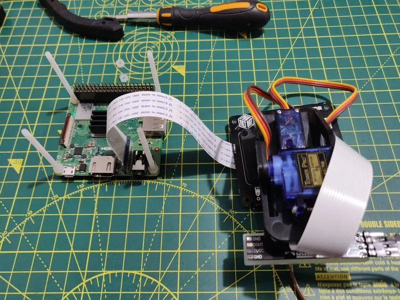 A Raspberry Pi 3A connected to a Pimoroni Pan-Tilt HAT which has a camera connect to it. The Pi has long nylon screws coming out of it. The start of building the robot CCTV system.