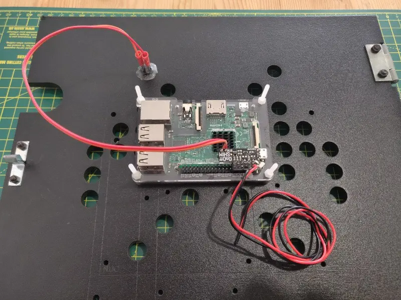 Hot gluing the button connecting the RaspberryPi On/Off shim to the interior of the rear cabinet door.