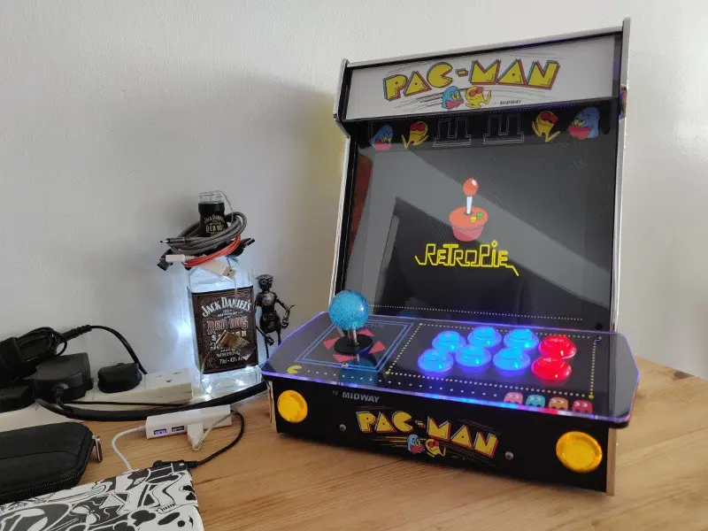 The completed cabinet shown from the front, all buttons illuminated and RetroPie booting.